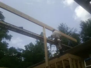 Carpenter setting a ridge beam over a new addition frame — Ice Dam Removal by Roofing Brothers in Armington