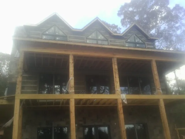 Dormers and porch framing on a large log home under construction — Roof Coating work by our crew in Armington