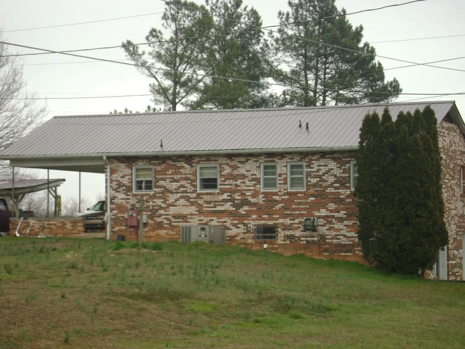 Gray metal roof on a brick split level home with a carport in Armington