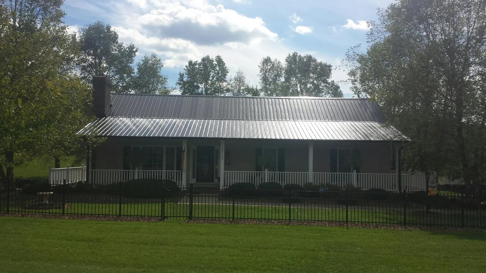 Gray metal roof on a brick ranch with a full width front porch — Gutter Guard Installation work by our crew in Armington