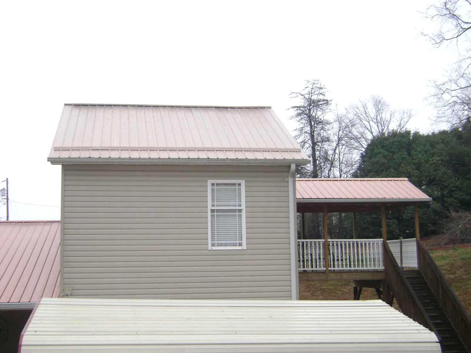 Tan metal roofs on a two story addition and attached porch, from a Roof Replacement job in Armington
