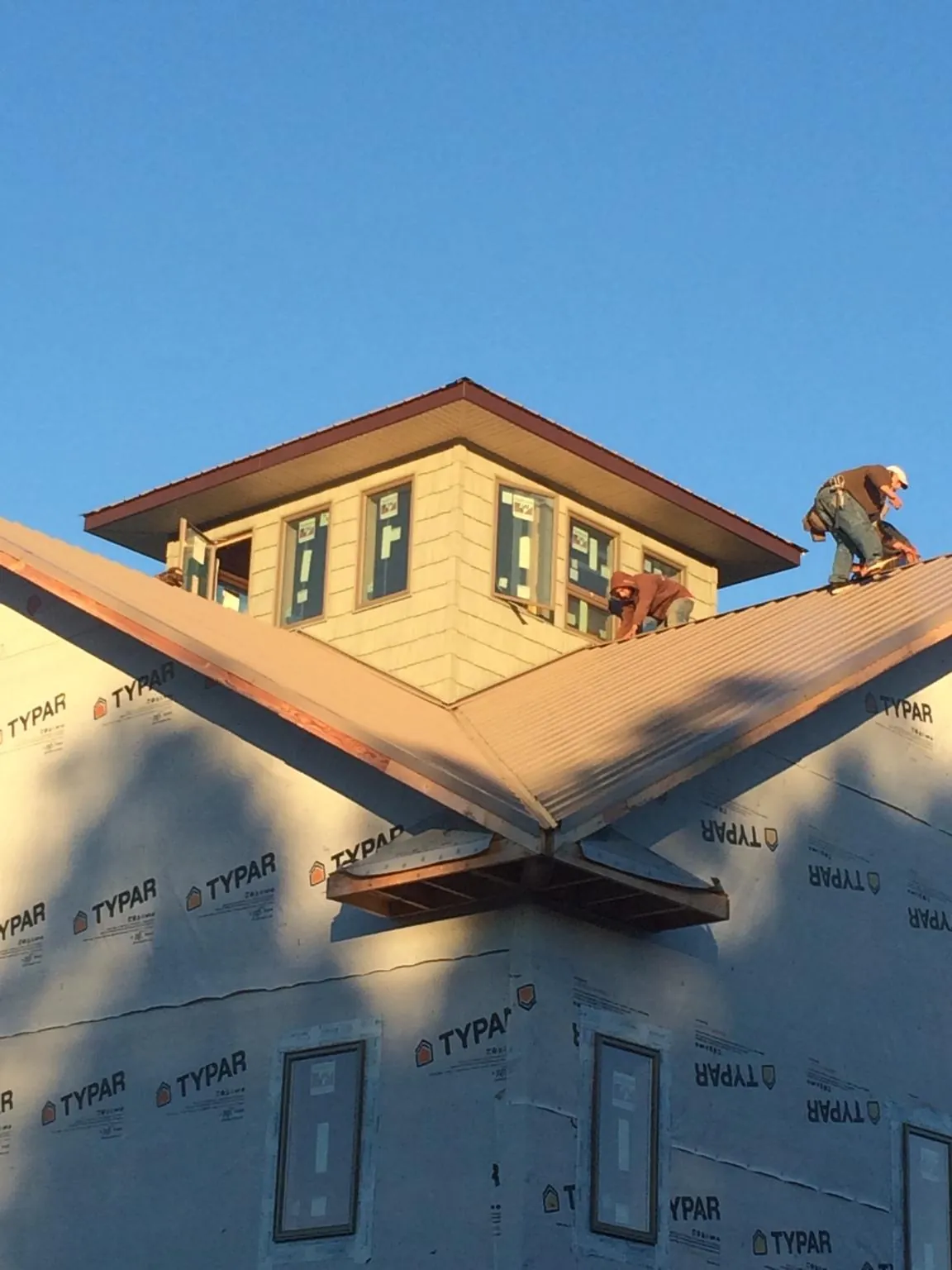 Roofers working around a rooftop cupola on a new metal roof at sunset — Roof Waterproofing in Armington by Roofing Brothers